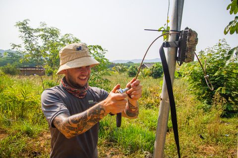 Tyler Nuckols tightening a steel cable on a roll-pole with a camera trap mounted at the top