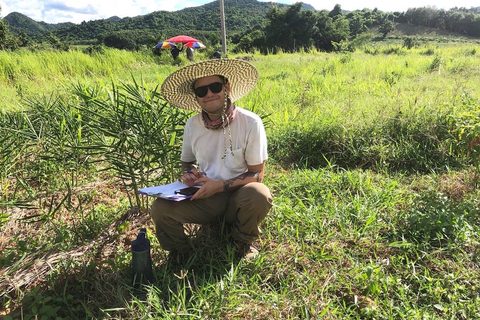 Tyler Nuckols with a clipboard in a field beside Kuiburi National Park