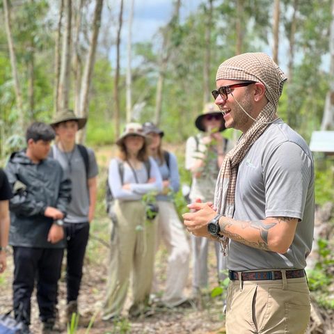 Tyler Nuckols talking with a group of field course students in a forest in Thailand